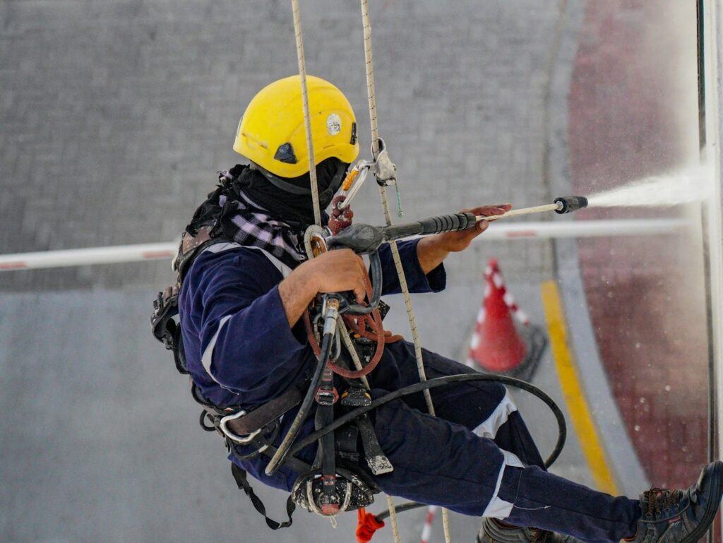 A man pressure washing a building.